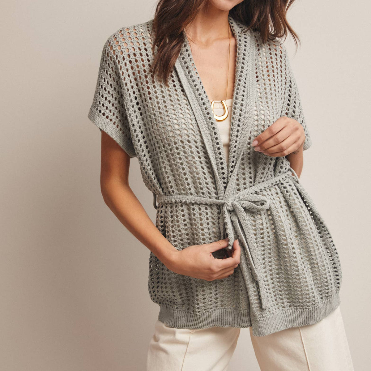 Woman wearing a Sage knit Cardigan with open knit and waist tie 