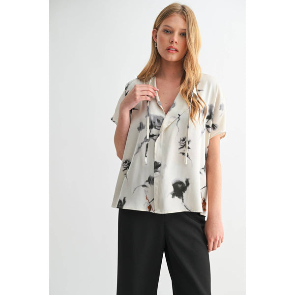 Woman wearing a floral blouse and black pants on a white background