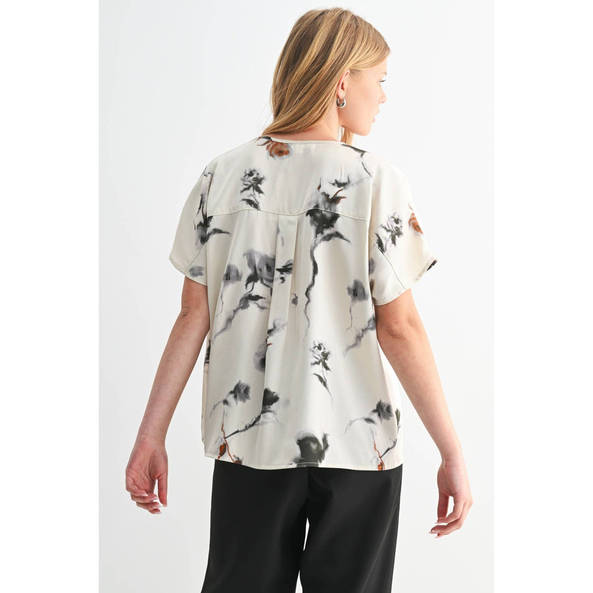 Woman wearing a white blouse with black floral pattern on a white background