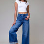 Woman wearing a white crop top and blue jeans on a plain background