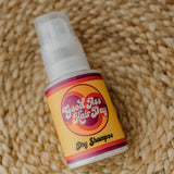 Bottle of 'Bad Ass Hair Day' dry shampoo on a textured woven surface