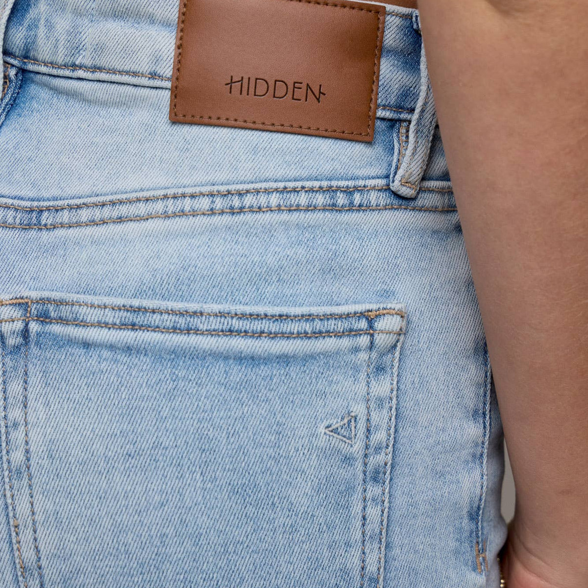 Close-up of light blue jeans with a brown label on the waistband.