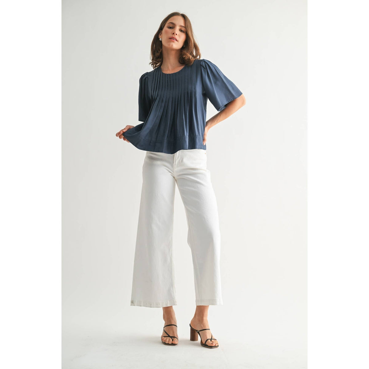 Woman wearing a blue top and white pants on a white background