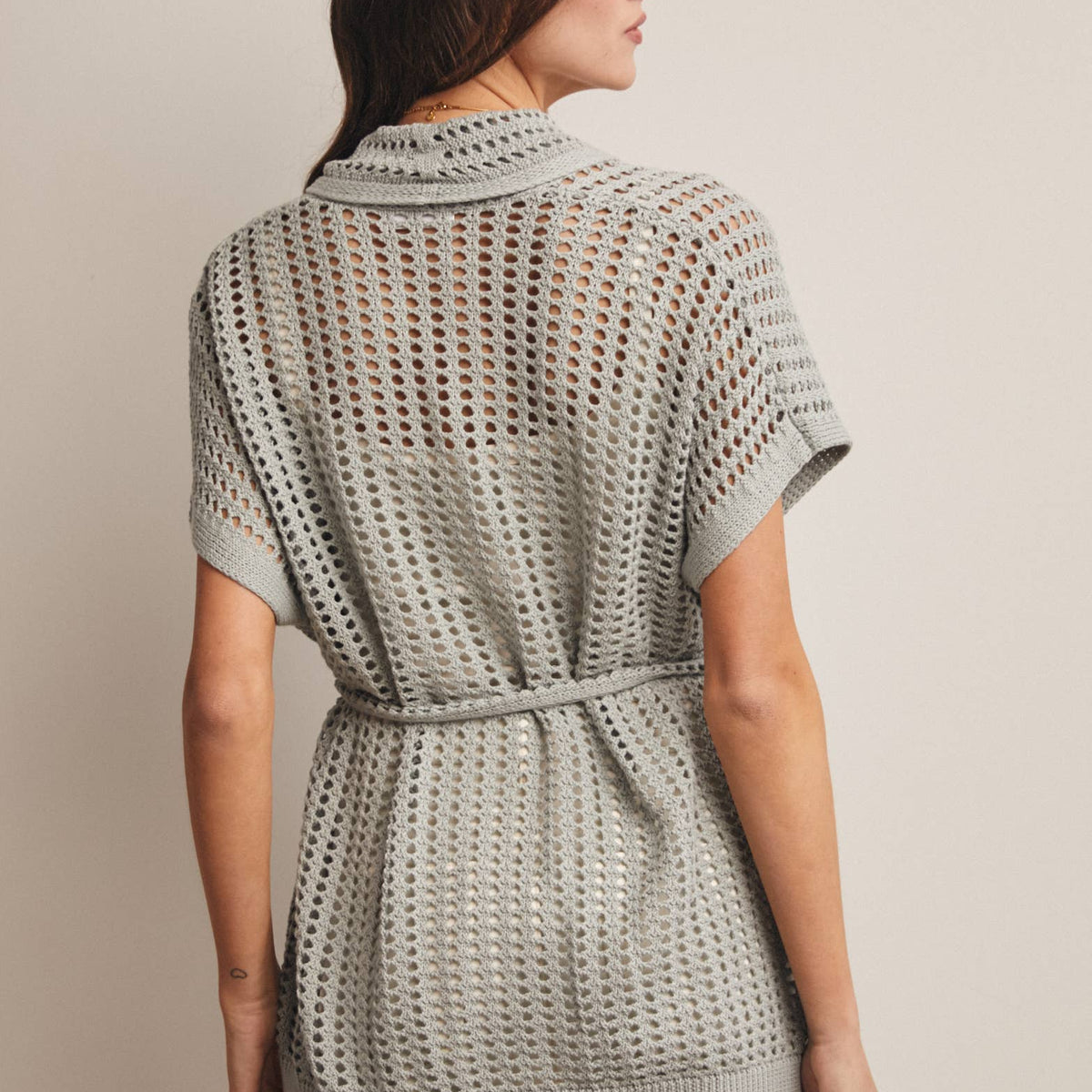 Woman wearing a Sage knit Cardigan with open knit and waist tie 