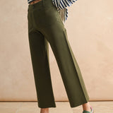 Person wearing green pants and striped shirt against a beige background