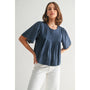 Woman wearing a blue blouse and white pants against a light background