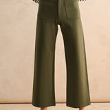 Person wearing green wide-leg pants and a striped shirt against a beige background