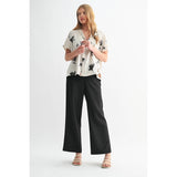 Woman wearing a floral blouse and black pants on a white background