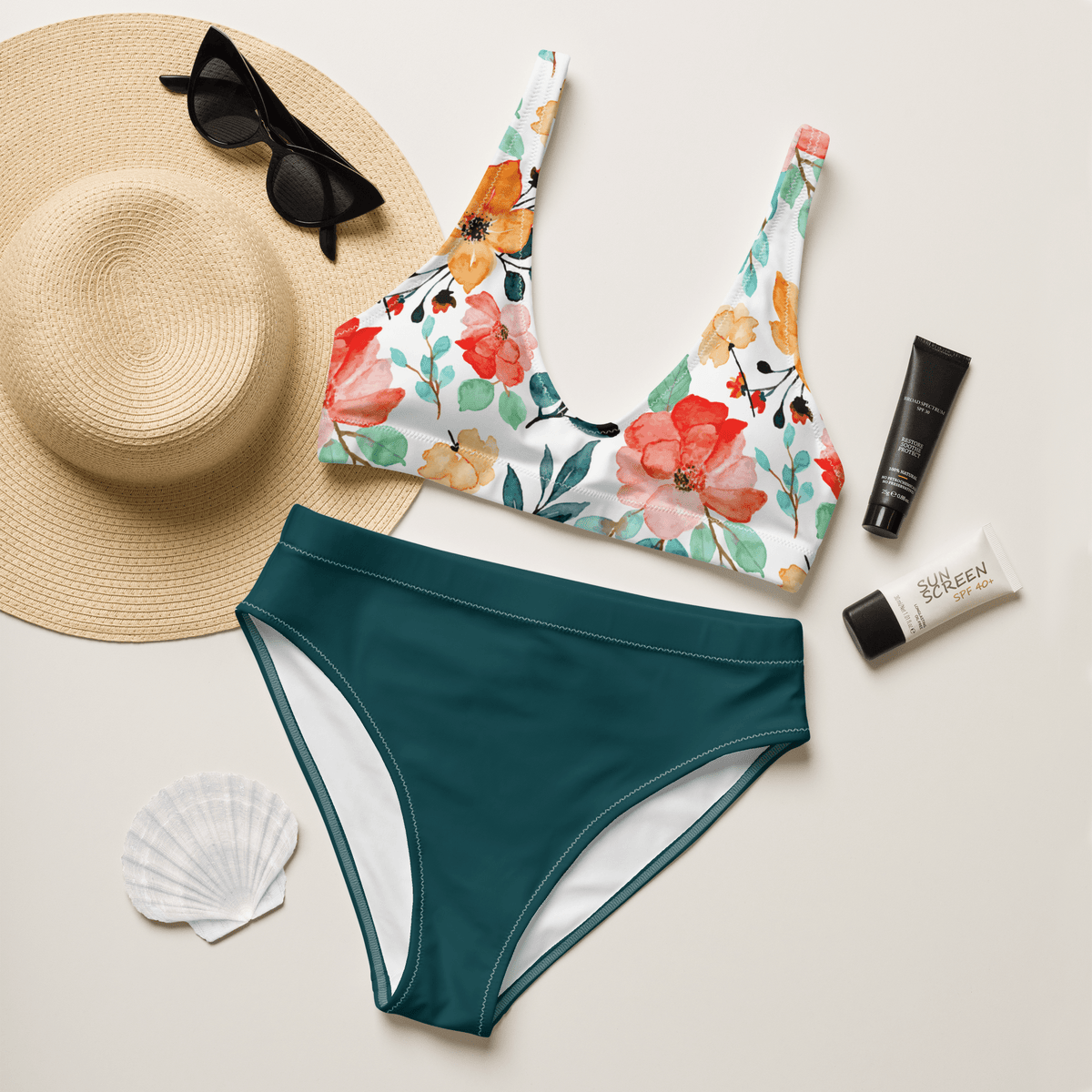 Floral bikini top and teal bottom with sun hat, sunglasses, sunscreen, and shell on a light background